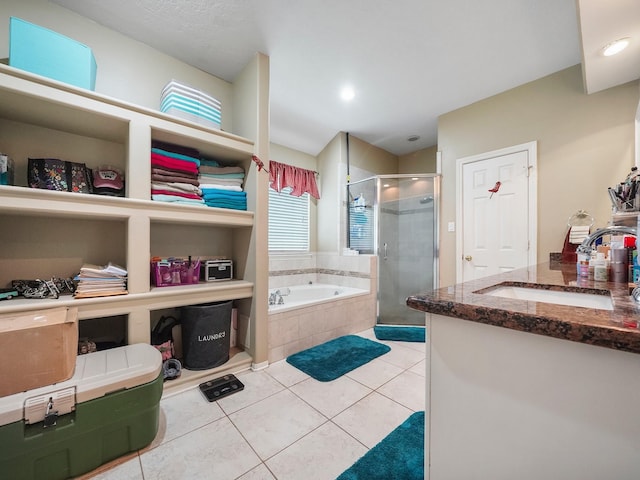 full bath with a stall shower, tile patterned flooring, a bath, and vanity