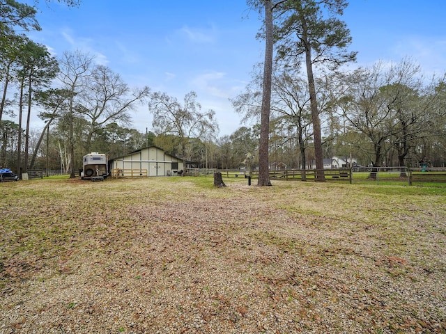 view of yard with a pole building, a rural view, and fence