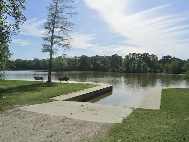 view of dock with a water view, a lawn, and a forest view