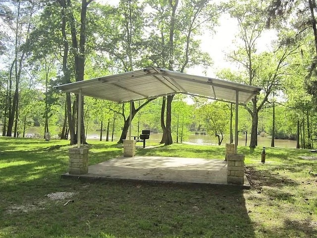 view of property's community with a patio, a detached carport, a water view, a lawn, and driveway