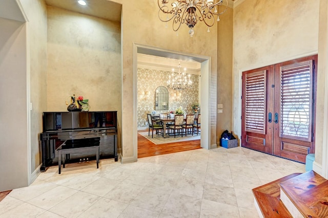 foyer with a high ceiling, a chandelier, and french doors