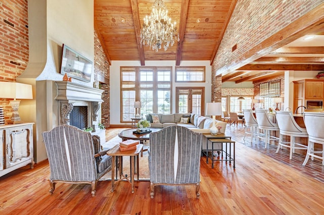 living area with high vaulted ceiling, light wood-type flooring, a fireplace, and beamed ceiling