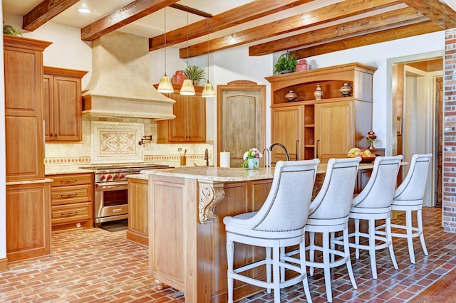 kitchen with decorative backsplash, a breakfast bar, decorative light fixtures, high end stainless steel range, and premium range hood