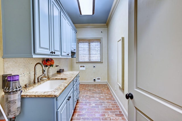 washroom with brick floor, a sink, cabinet space, electric dryer hookup, and crown molding