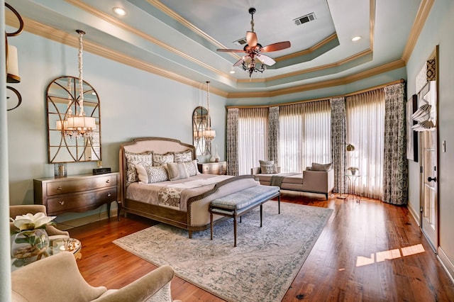 bedroom featuring a tray ceiling, a notable chandelier, wood-type flooring, visible vents, and ornamental molding