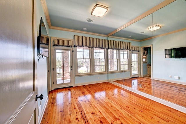 interior space featuring baseboards, wood-type flooring, visible vents, and crown molding