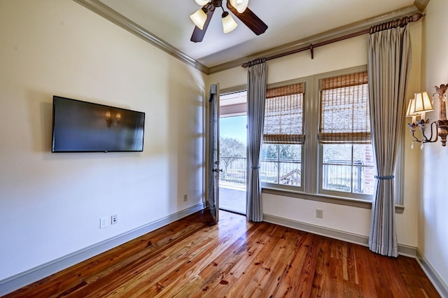 unfurnished room with ceiling fan, crown molding, baseboards, and wood finished floors