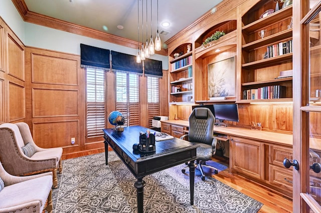 office featuring ornamental molding, light wood-type flooring, built in study area, and visible vents