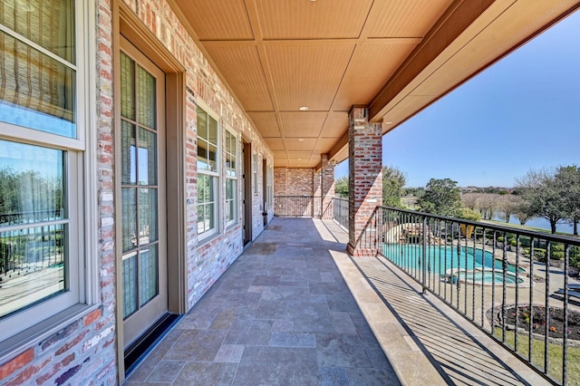 balcony with an in ground hot tub and a patio