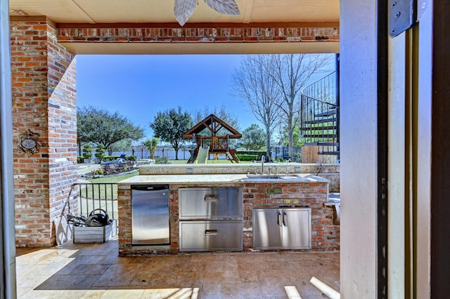 view of patio / terrace with a playground, stairway, an outdoor kitchen, a sink, and fence