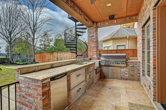 view of patio / terrace with grilling area, fence, a sink, exterior kitchen, and stairs