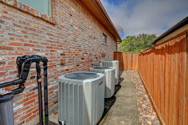 details featuring brick siding, a fenced backyard, and central air condition unit