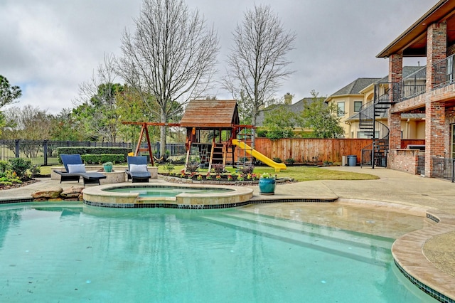 view of pool with a patio area, a playground, fence, and a pool with connected hot tub