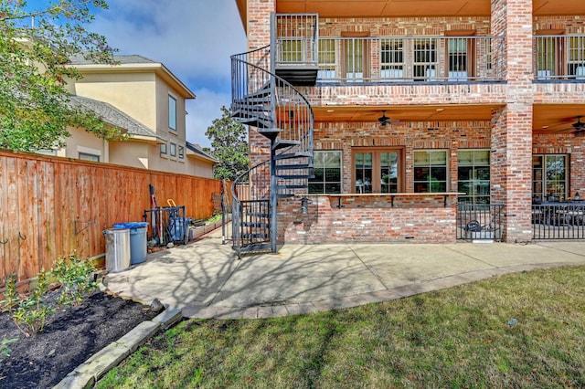 rear view of property with a ceiling fan, brick siding, a patio, and stairway