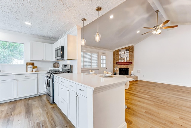 kitchen with white cabinets, open floor plan, stainless steel appliances, light countertops, and light wood-style floors