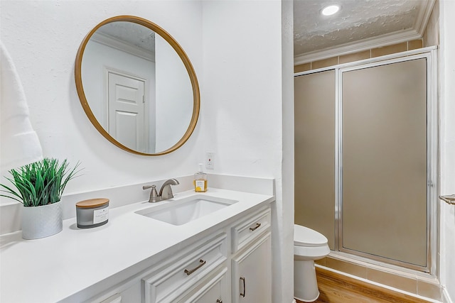 full bathroom with vanity, ornamental molding, wood finished floors, toilet, and a shower stall