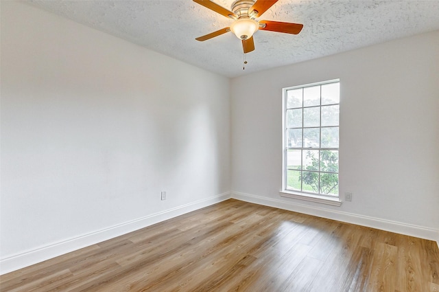 unfurnished room featuring light wood-style floors, baseboards, ceiling fan, and a textured ceiling