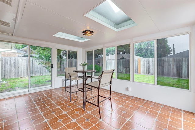 sunroom / solarium with a skylight, tile patterned flooring, and plenty of natural light