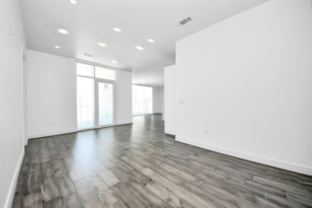 empty room with baseboards, visible vents, dark wood-style flooring, and recessed lighting