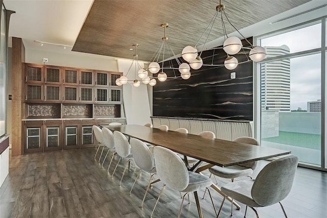 dining room with dark wood-type flooring, a healthy amount of sunlight, and an inviting chandelier