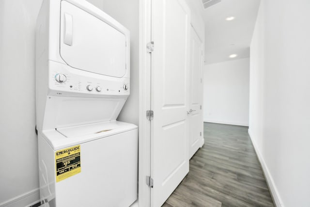 laundry area featuring recessed lighting, laundry area, wood finished floors, baseboards, and stacked washer and clothes dryer