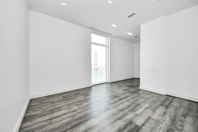 spare room featuring recessed lighting, wood finished floors, visible vents, and baseboards