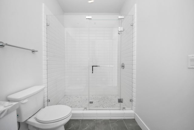 bathroom with toilet, a stall shower, and baseboards