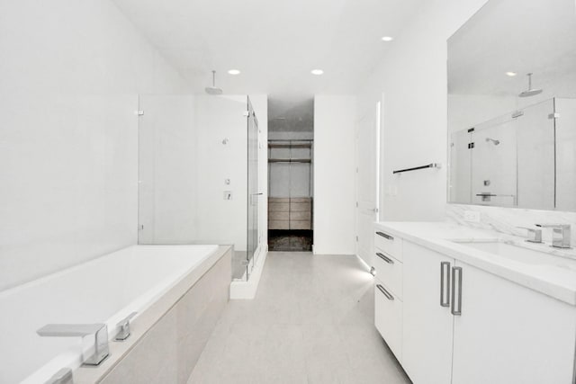 bathroom featuring recessed lighting, vanity, a bath, a stall shower, and a walk in closet