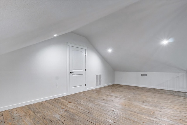 additional living space with lofted ceiling, baseboards, visible vents, and light wood finished floors