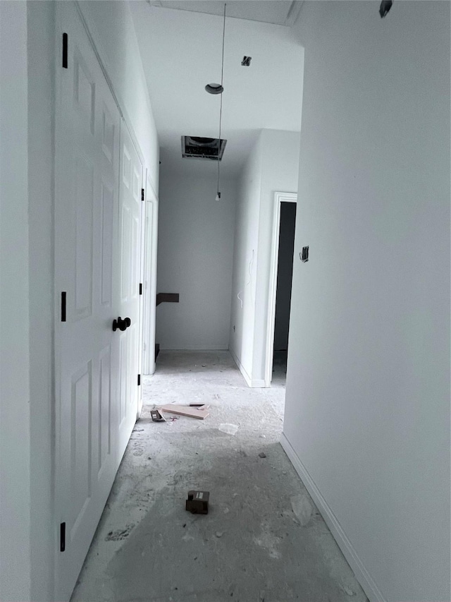 hallway featuring attic access and baseboards