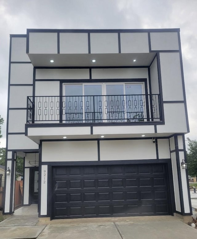 view of front of home with a balcony, an attached garage, stucco siding, and driveway