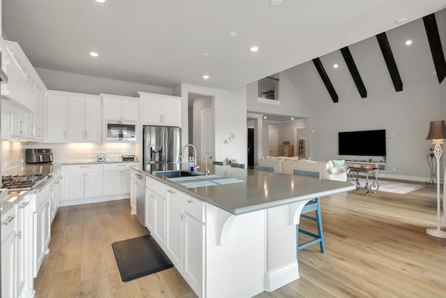 kitchen featuring stainless steel appliances, white cabinets, a large island, and a breakfast bar area