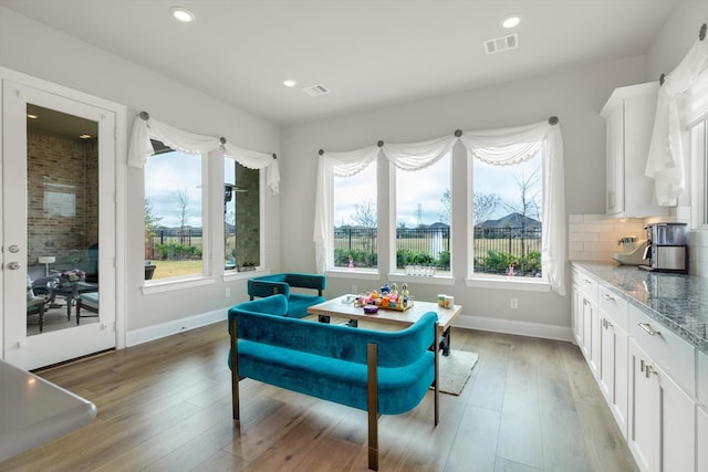 living area with light wood-style floors, visible vents, and baseboards