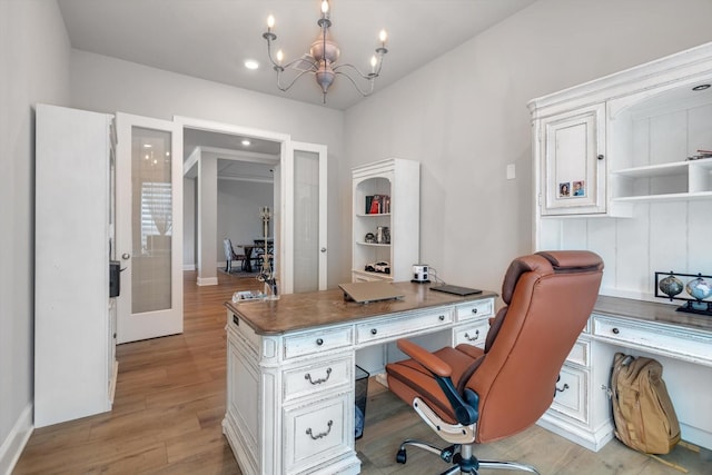 office space featuring french doors, light wood finished floors, and an inviting chandelier