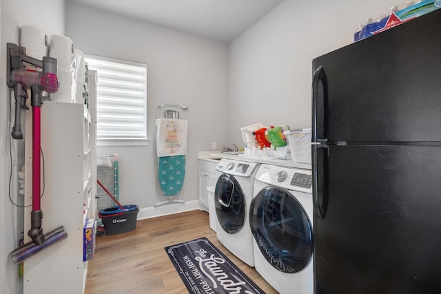 laundry room with light wood-style floors, baseboards, washer and clothes dryer, and a sink