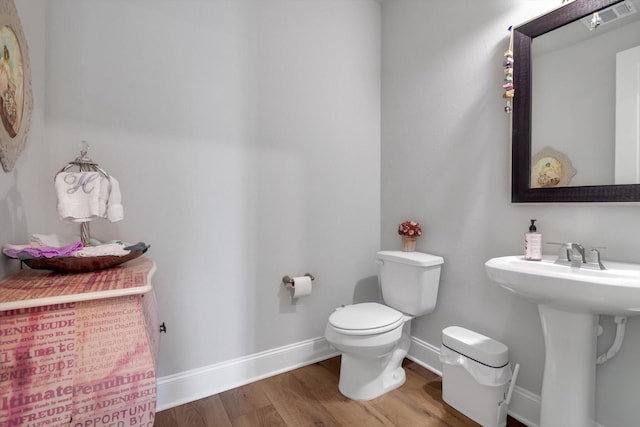 bathroom featuring toilet, a sink, visible vents, wood finished floors, and baseboards