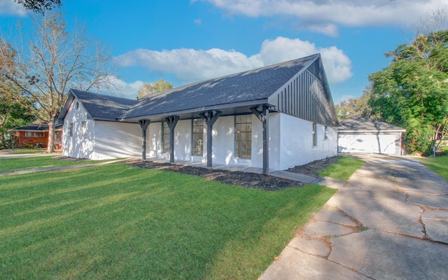 view of front of property featuring a front yard, covered porch, brick siding, and a detached garage