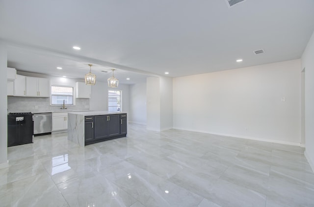 kitchen with white cabinets, open floor plan, light countertops, stainless steel dishwasher, and decorative light fixtures