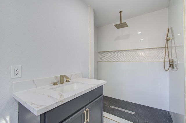 full bathroom featuring a tile shower and vanity