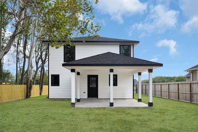 rear view of house with a yard, roof with shingles, a patio area, and a fenced backyard