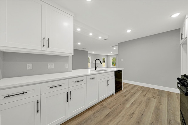 kitchen with white cabinets, light countertops, light wood-style floors, a sink, and recessed lighting