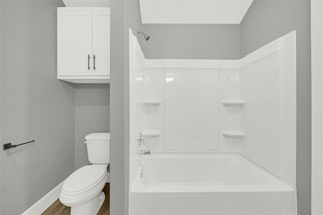 bathroom featuring toilet, shower / bath combination, baseboards, and wood finished floors