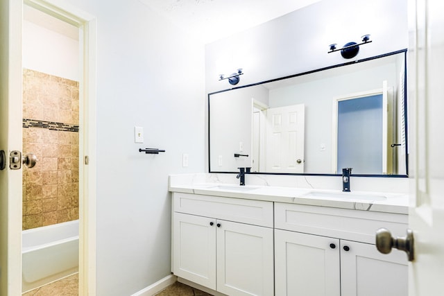 bathroom featuring double vanity, tile patterned flooring, a sink, and baseboards