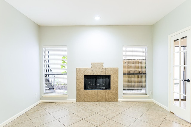 unfurnished living room featuring light tile patterned floors, a fireplace, and baseboards