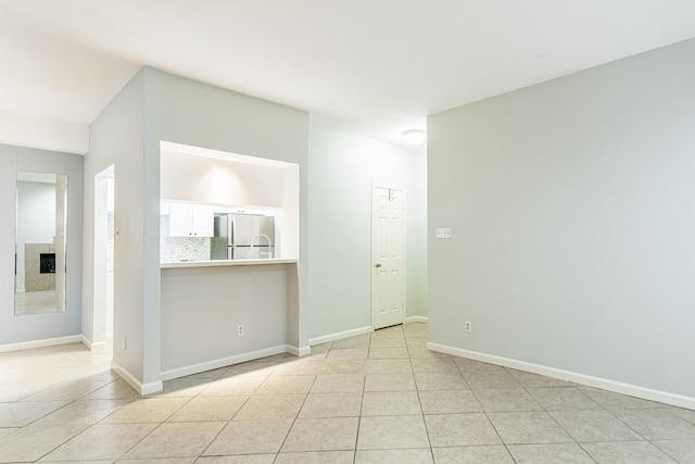 spare room featuring light tile patterned flooring, a fireplace, and baseboards