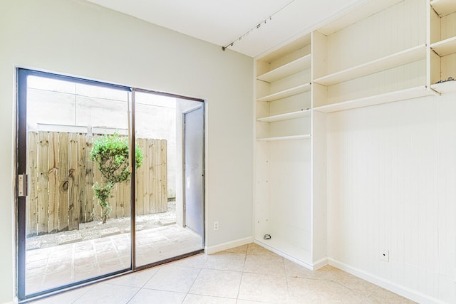 doorway featuring tile patterned flooring, built in shelves, and baseboards