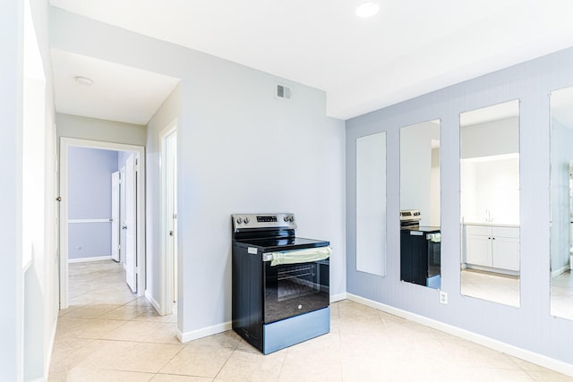 interior space with visible vents, electric range, electric range oven, light tile patterned flooring, and baseboards