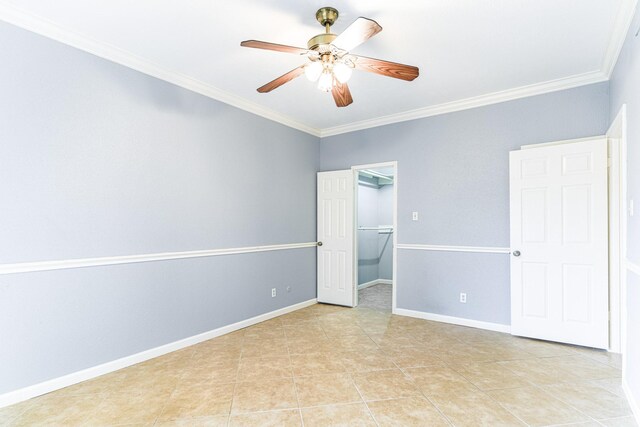 unfurnished bedroom featuring ornamental molding, a walk in closet, baseboards, and light tile patterned floors