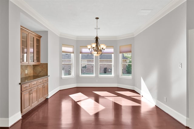 unfurnished dining area featuring a chandelier, dark wood-type flooring, ornamental molding, and baseboards