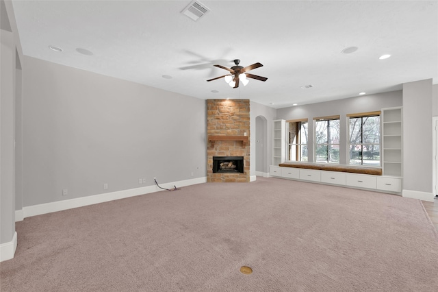 unfurnished living room featuring light carpet, baseboards, visible vents, ceiling fan, and a stone fireplace